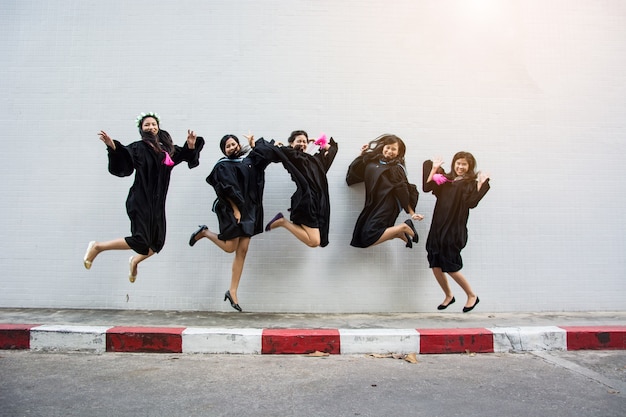 Students celebrating graduation in caps and gowns, throwing their mortarboards in the air against a clear blue sky, emphasizing the achievement and future prospects made possible by educational support.