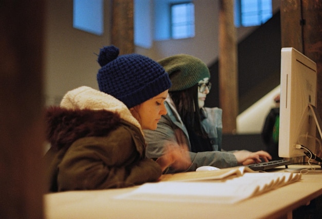 Close-up shot of a young student in a US school, focusing on their hands typing on a laptop. The background is slightly blurred, showing other students working quietly in the classroom. This image highlights the hands-on technology experience that educators are working hard to make sure is equally available to everyone.