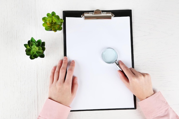 A person holding a magnifying glass over an application form, emphasizing the need for careful review and accuracy when applying for disability benefits.