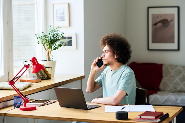 A person sitting at a desk, talking on the phone while looking at a computer screen displaying information about affordable housing resources.