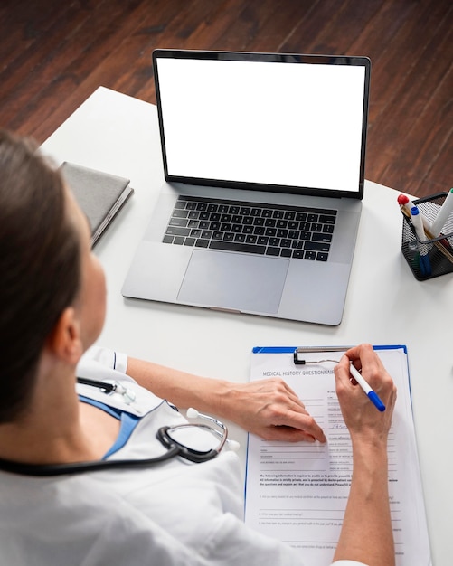 A person reviewing a Medicare enrollment form at their desk, with a pen in hand and a laptop showing information about enrollment periods.