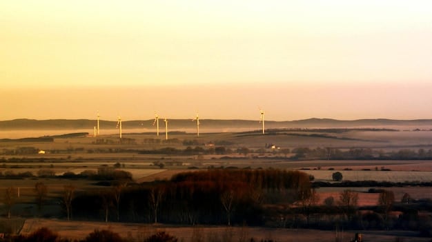 A modern wind turbine farm at sunset, representing investments in sustainable infrastructure and clean energy solutions.