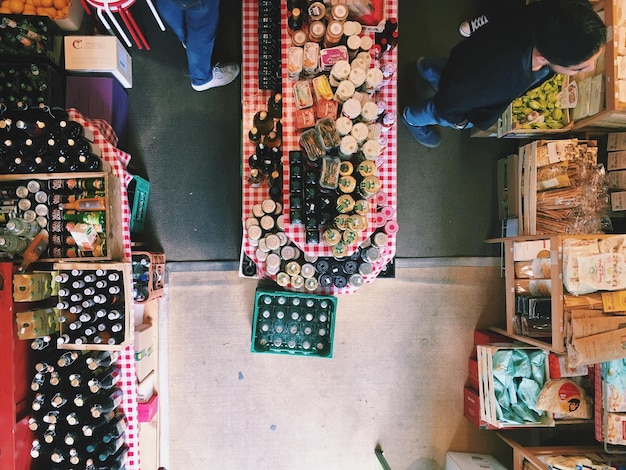 An aerial view inside a bustling local farmers market, where vendors are selling fresh produce, baked goods, and homemade jams. Customers are paying with SNAP EBT cards at various stalls.