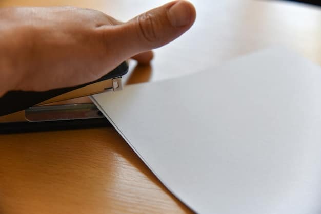 A close-up of a hand filling out an unemployment claim form, with a pen hovering over the signature line, emphasizing the application process.