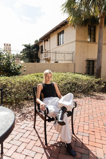 A cozy, well-maintained senior housing complex on a sunny day. The building features manicured lawns, colorful flower beds, and comfortable benches for residents to relax outdoors. Several seniors are seen enjoying the communal garden, smiling and engaging in conversation.