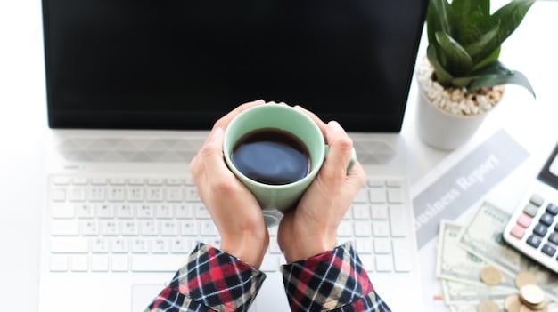 A person making an online contribution to their 401(k) account, with a calculator and a coffee cup on the desk, symbolizing planning and saving for retirement.